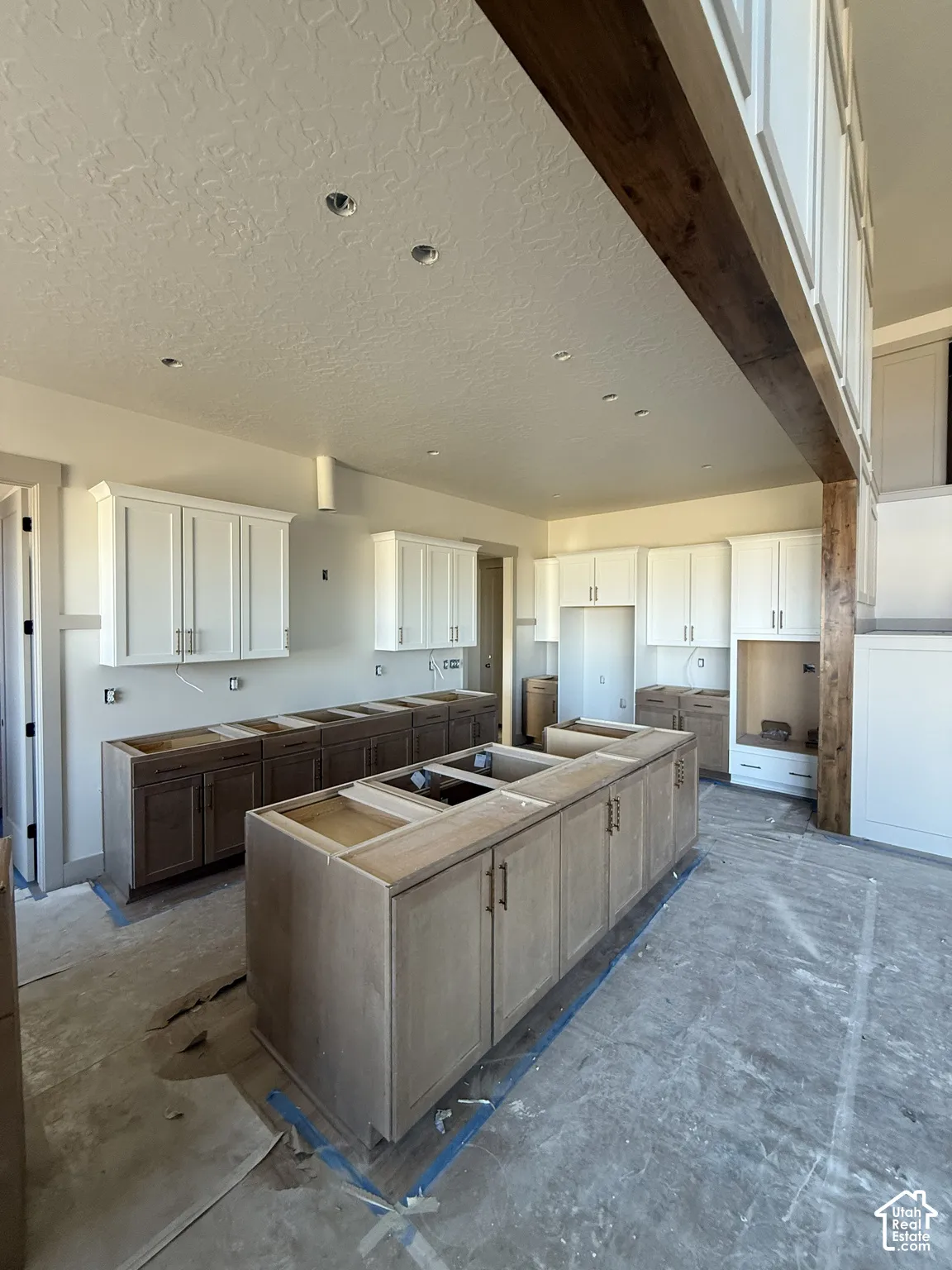 Kitchen featuring custom cabinetry with a two-tone finish, large central island, recessed lighting, and a prominent decorative timber ceiling beam