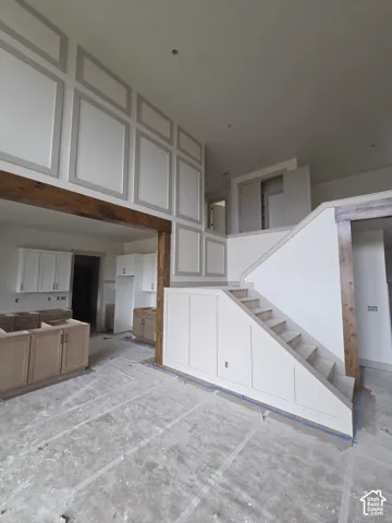 High-ceiling interior featuring extensive wall paneling, custom-stained wood beams, and a staircase with integrated panel-front cabinetry