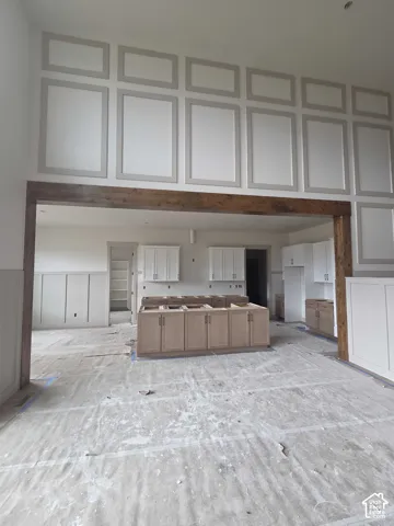 Expansive ceiling height featuring decorative wall molding and a natural wood-finish structural beam
