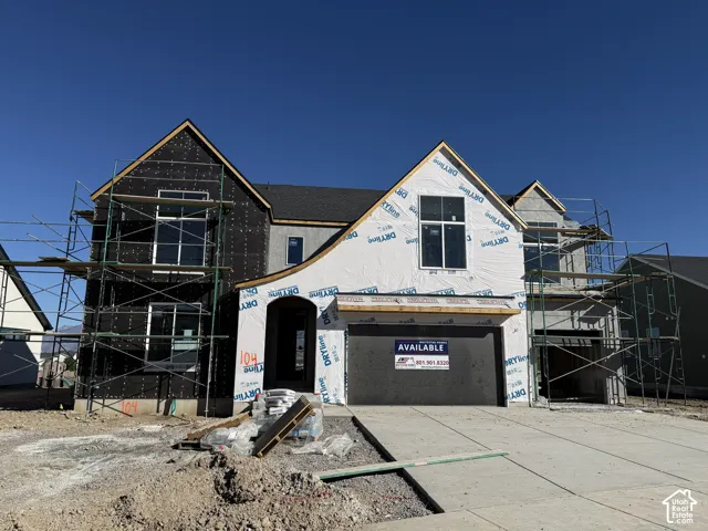 Multi-level exterior featuring a combination of roof peaks, double-car and single-car garage bays, and multi-pane windows