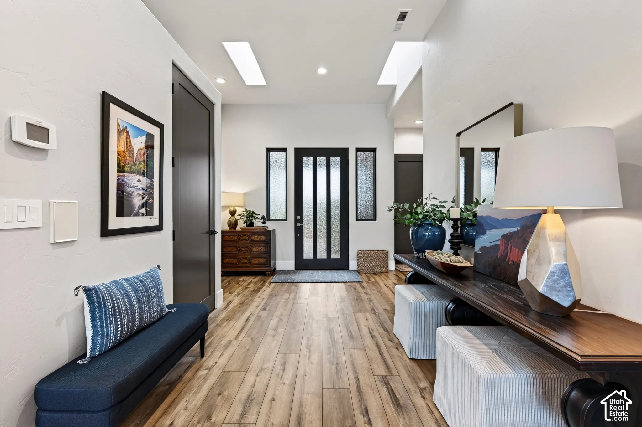 Wood-finish flooring, recessed lighting, and a modern entryway door with frosted glass panels