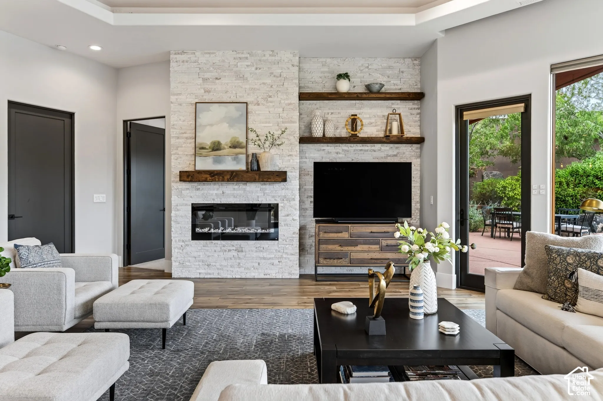 Living area featuring a floor-to-ceiling stacked stone fireplace, a dark wood mantel, built-in open shelving, and wood-finish flooring