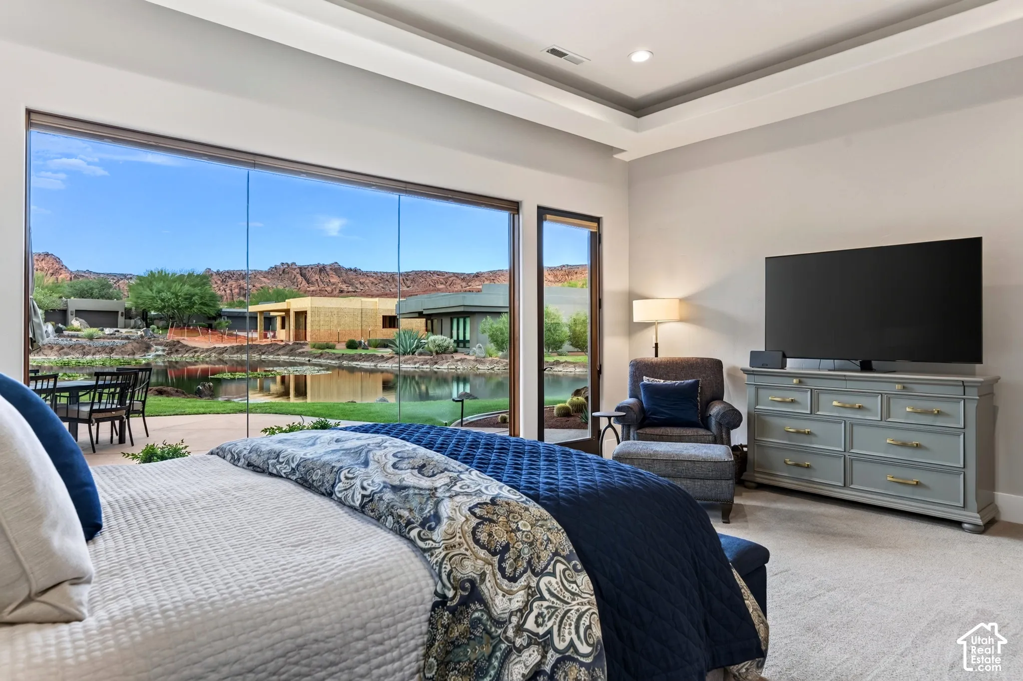 Primary Bedroom:  Floor-to-ceiling glass wall, recessed lighting, tray ceiling, outdoor patio, and water feature