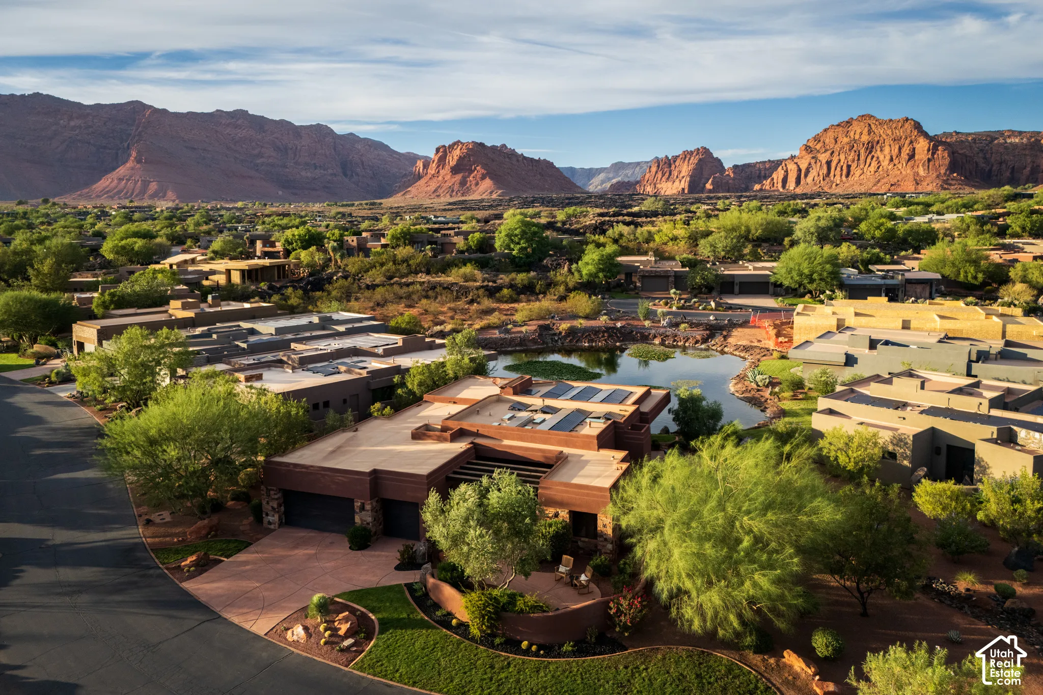 Modern desert architecture with flat roofs and solar panels, featuring extensive mature landscaping and natural rock elements
