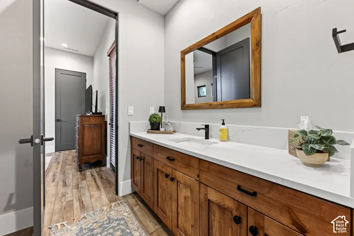 Jack and Jill Bath w/ Shower (not shown): Wood-finish flooring, vanity with wood cabinetry, white countertop, rectangular undermount sink, and wall-mounted wooden frame mirror