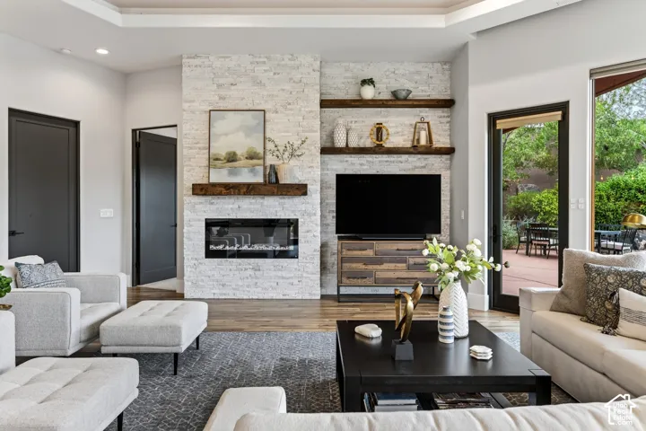 Living area featuring a floor-to-ceiling stacked stone fireplace, a dark wood mantel, built-in open shelving, and wood-finish flooring