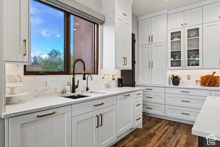 White shaker cabinetry complemented by gold-tone and matte black hardware, undercabinet lighting, and wood-finish flooring