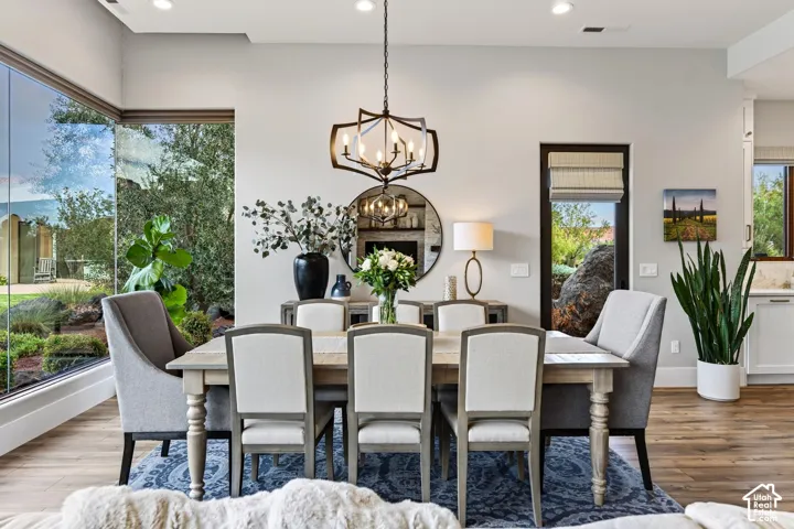 Floor-to-ceiling corner windows, wood-finish flooring, recessed lighting, and a modern chandelier