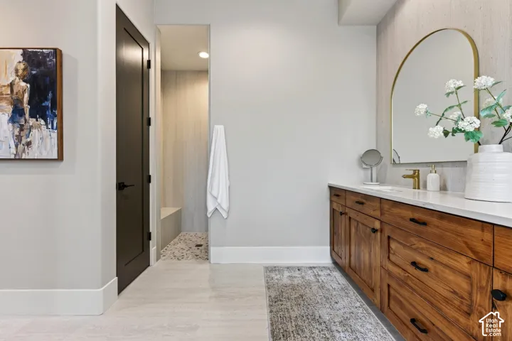 Primary Bathroom: His and Her Closets to the left, not photographed.  Long wood-finish vanity with a white countertop and integrated sink