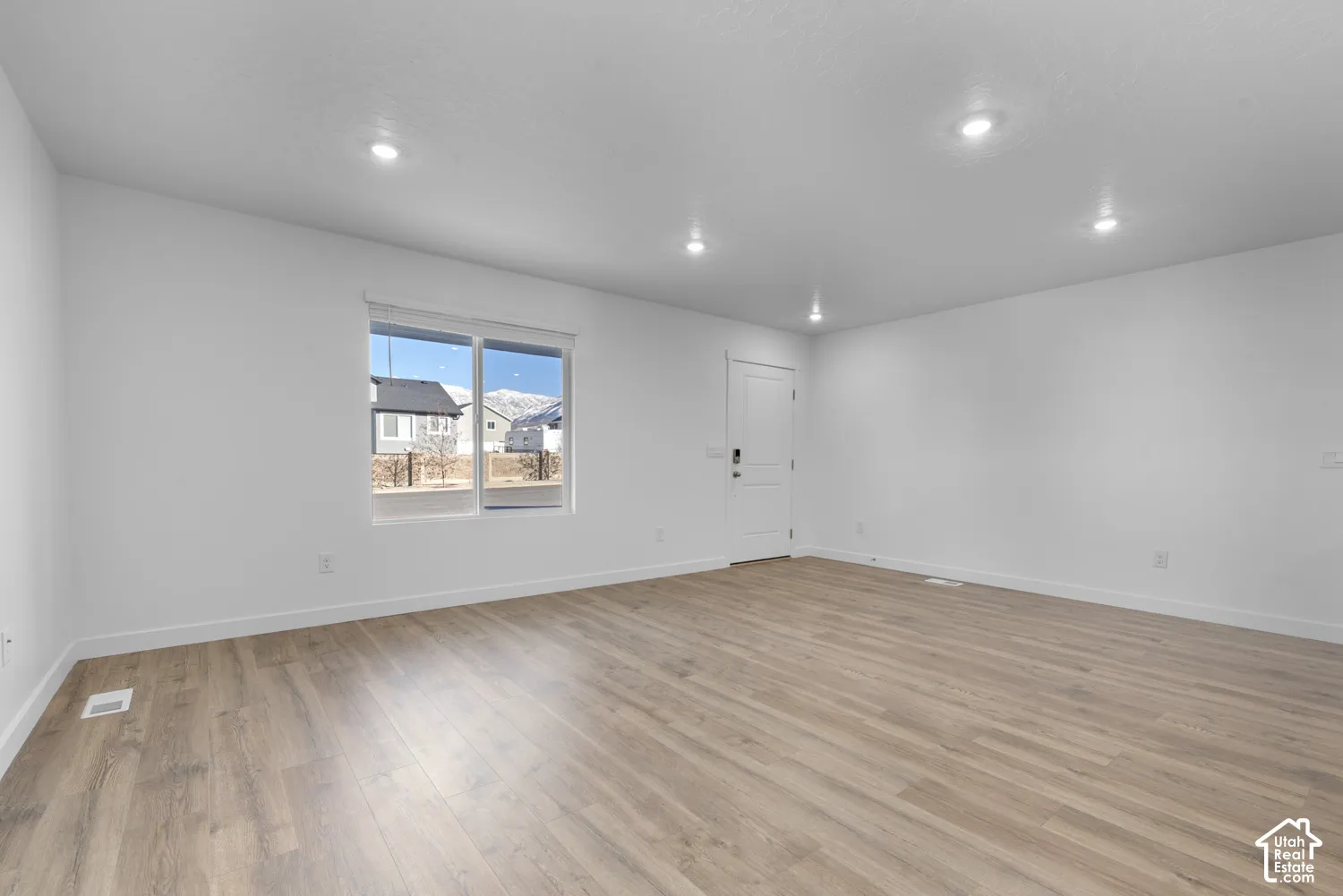 Recessed lighting, wood-finish flooring, white walls, and a multi-pane window