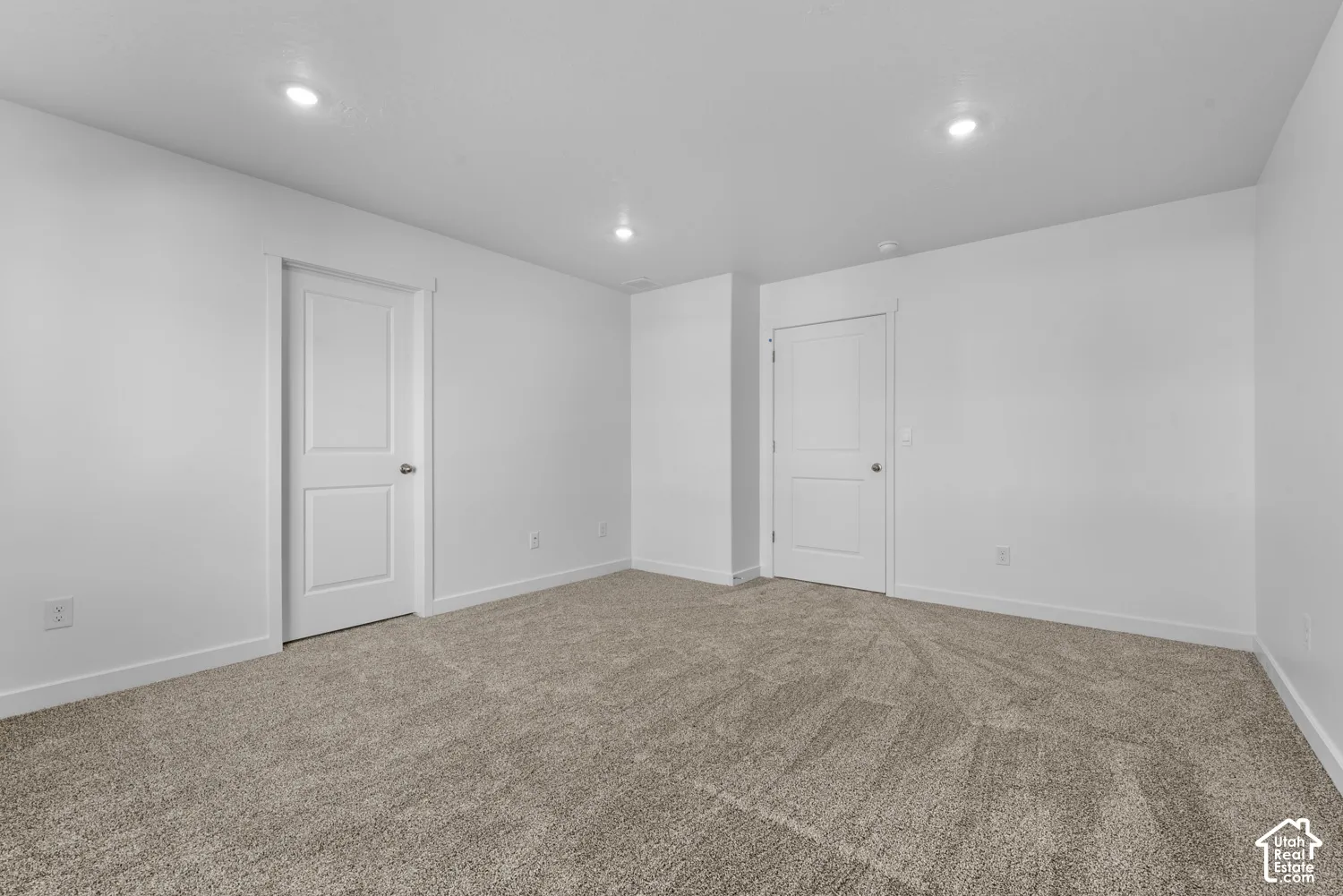 Neutral tone carpet flooring, recessed ceiling lighting, and solid core doors