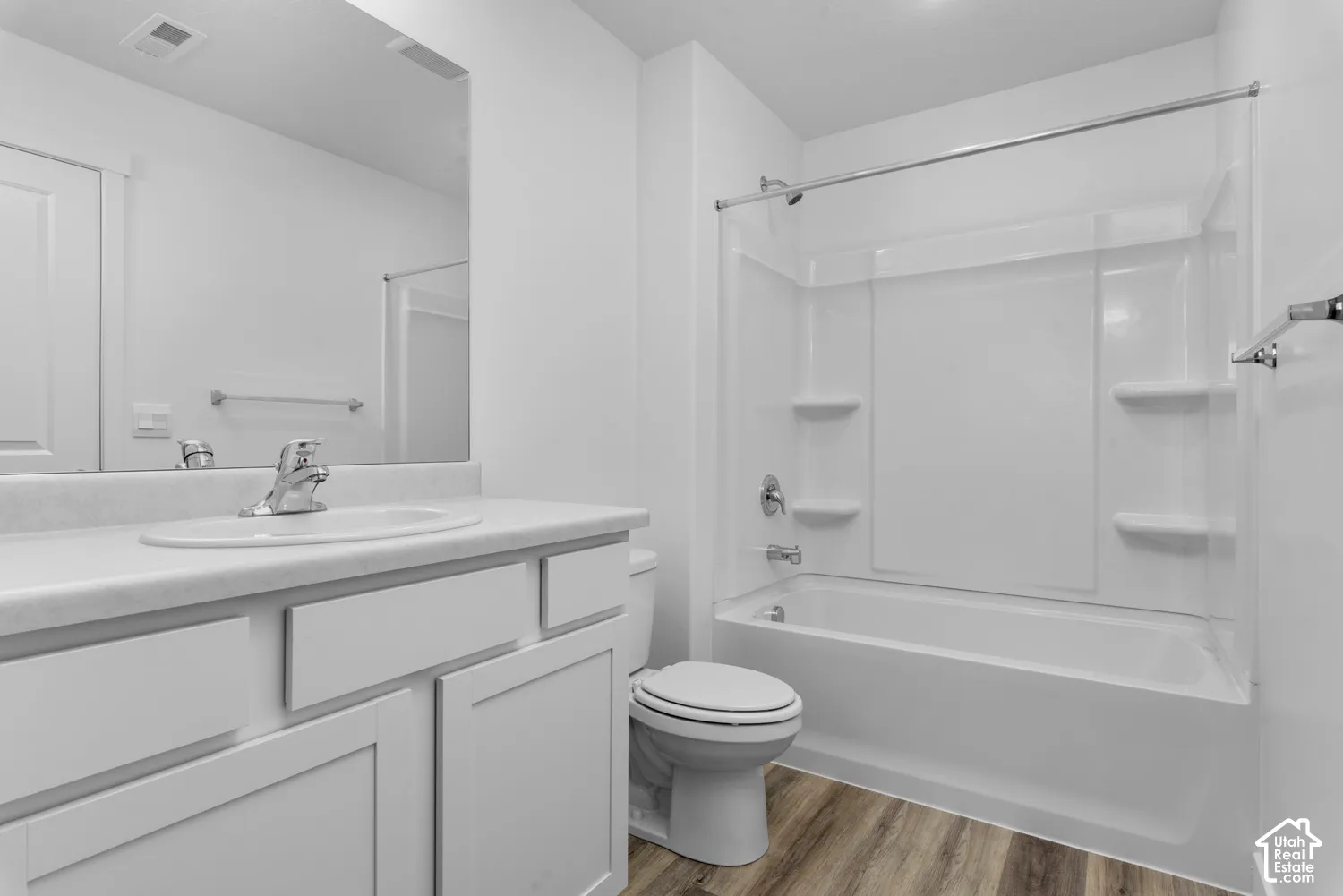 White vanity with an integrated sink, polished chrome faucet, and wood-finish flooring