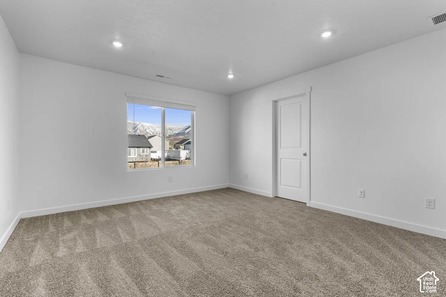 Recessed lighting, neutral wall finishes, light-toned carpet, white trim, and a mountain backdrop