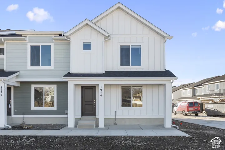 Multi-level townhome with a dark entry door, white columns, and siding