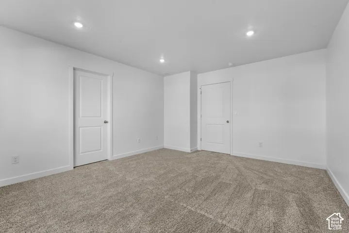 Neutral tone carpet flooring, recessed ceiling lighting, and solid core doors