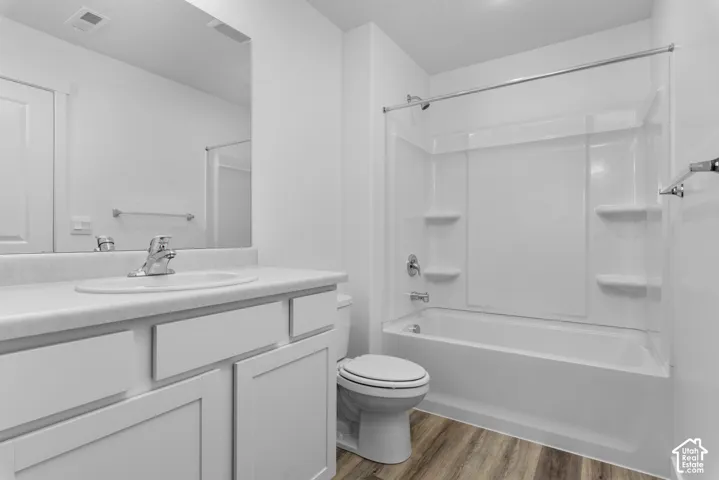 White vanity with an integrated sink, polished chrome faucet, and wood-finish flooring