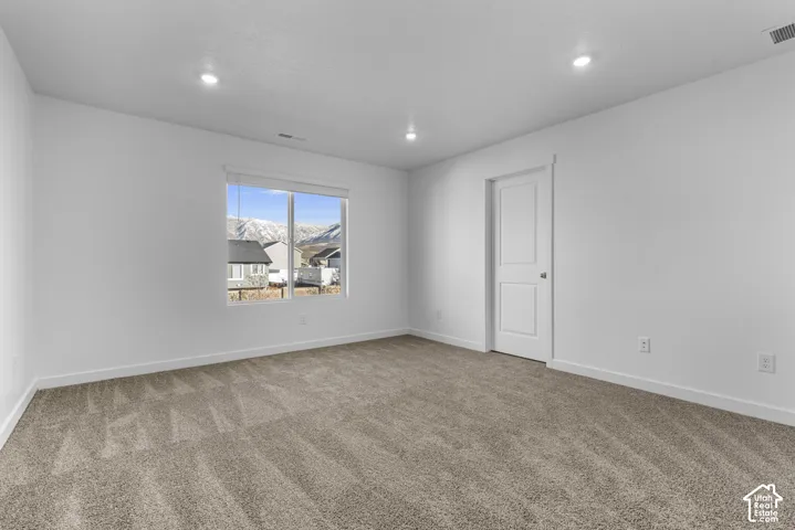 Recessed lighting, neutral wall finishes, light-toned carpet, white trim, and a mountain backdrop