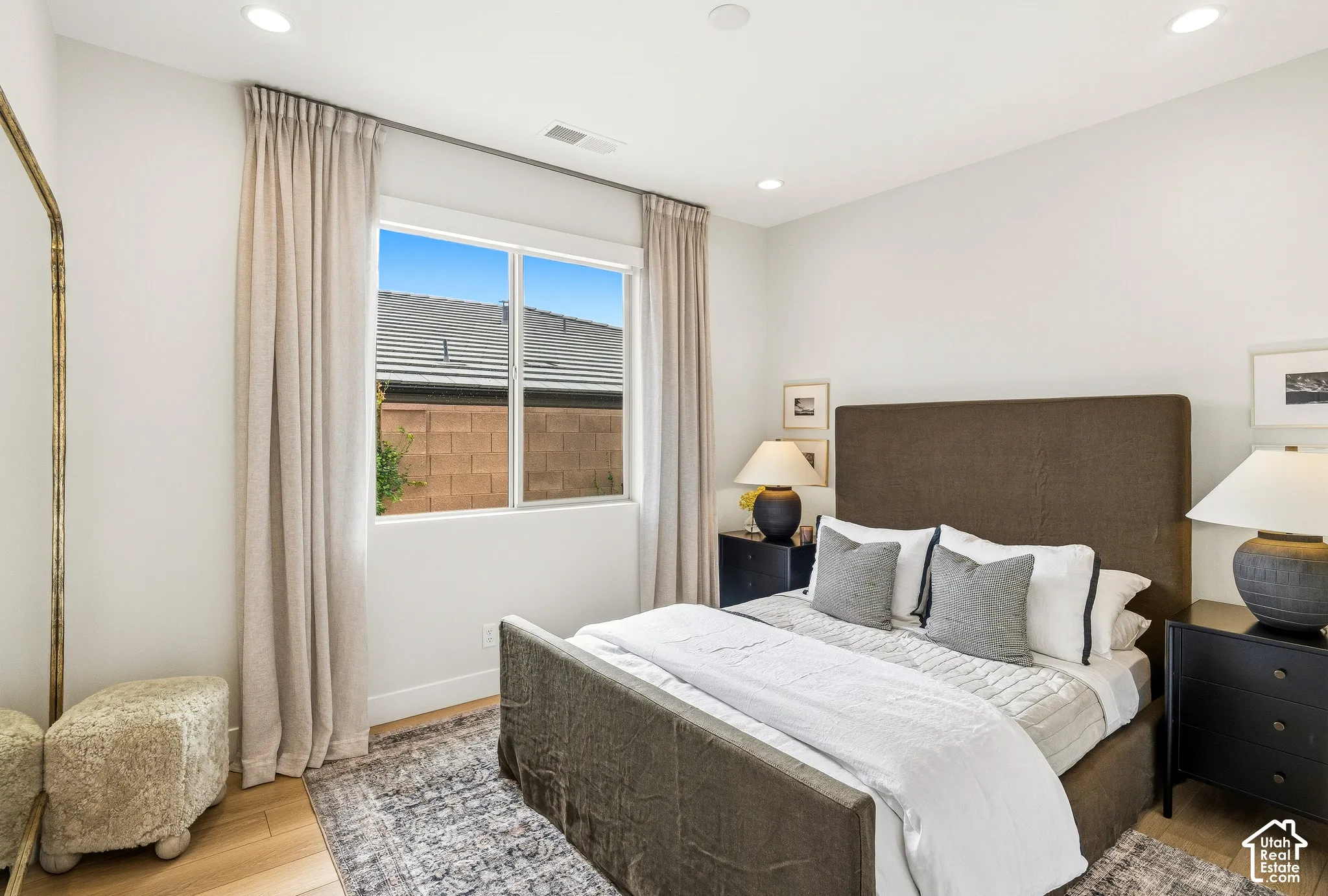 Recessed ceiling lighting, wood-finish flooring, and a large window with privacy blinds
