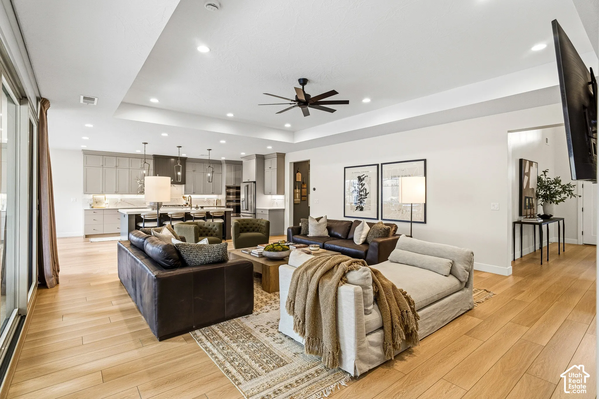 Open-concept living area featuring wood-finish flooring, recessed lighting, and a tray ceiling