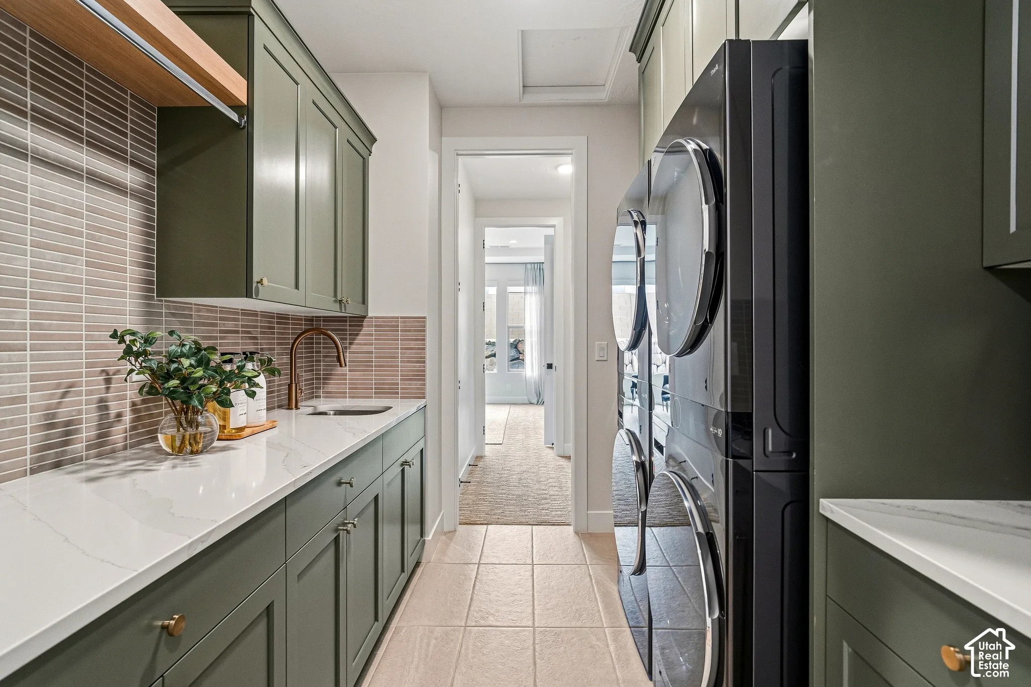 Integrated laundry area featuring olive green cabinetry, a white countertop, and a brass-finish faucet with a rectangular undermount sink