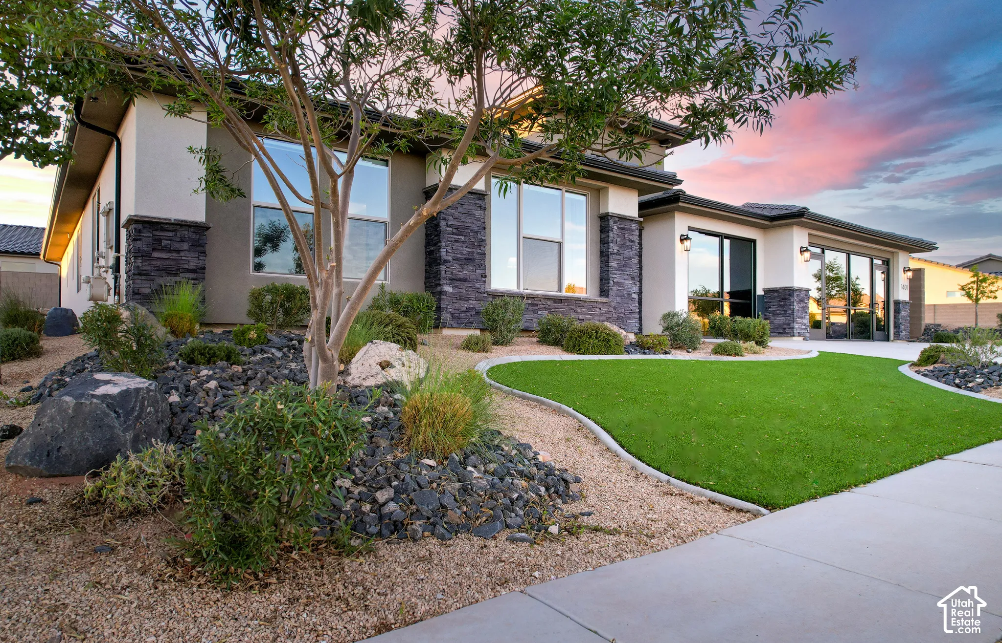 Stucco exterior with stone accents, professional landscaping, artificial turf, mature tree, and concrete walkway