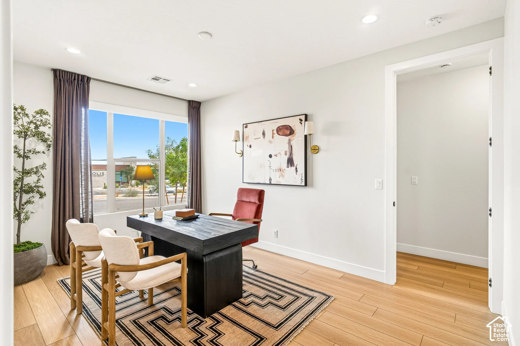 Bright room featuring wood-finish flooring, recessed lighting, a large window, and a doorway