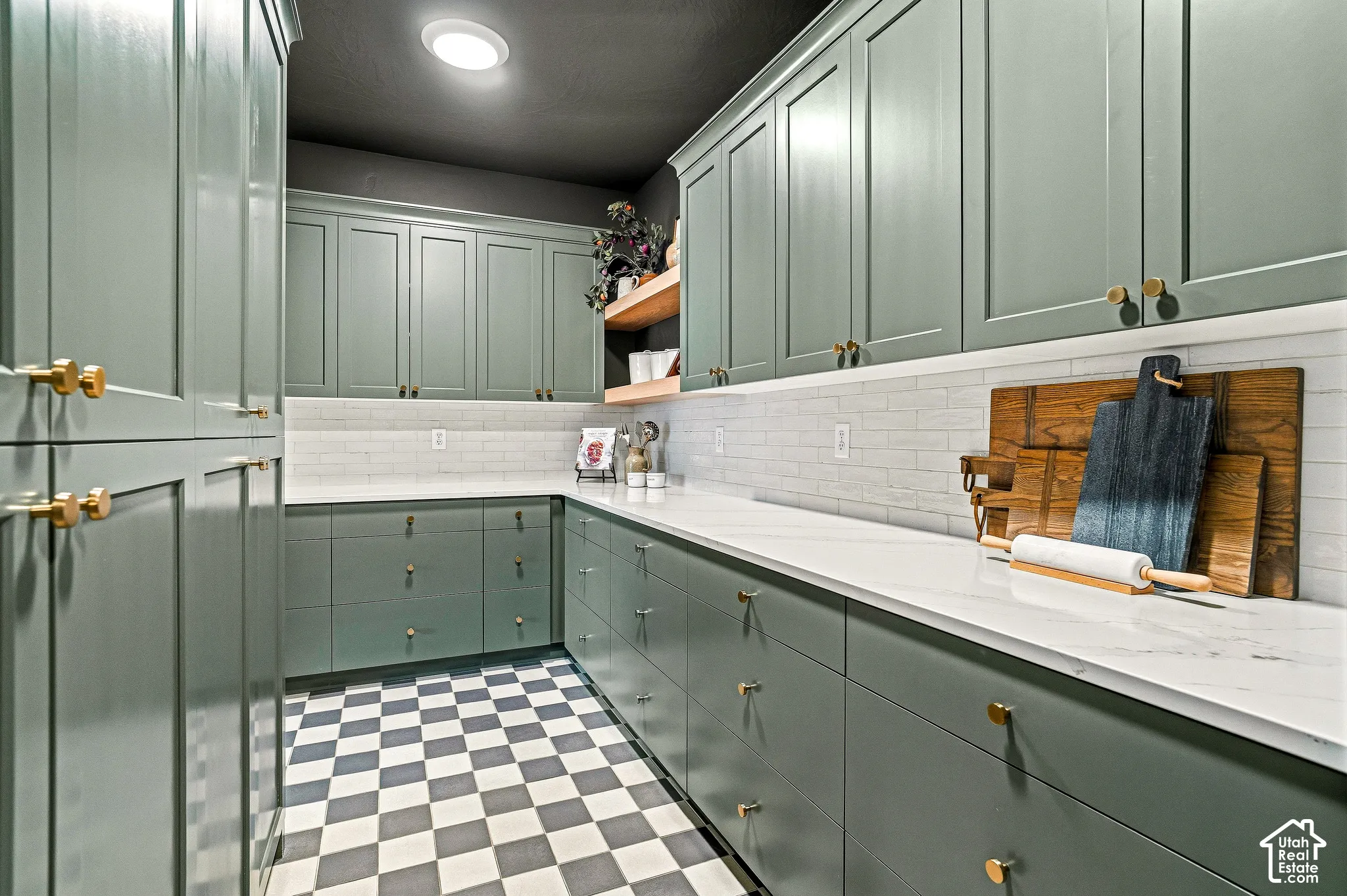 Extensive cabinetry with gold-tone hardware, white countertops, white subway tile backsplash, recessed lighting, and checkerboard floor tiling