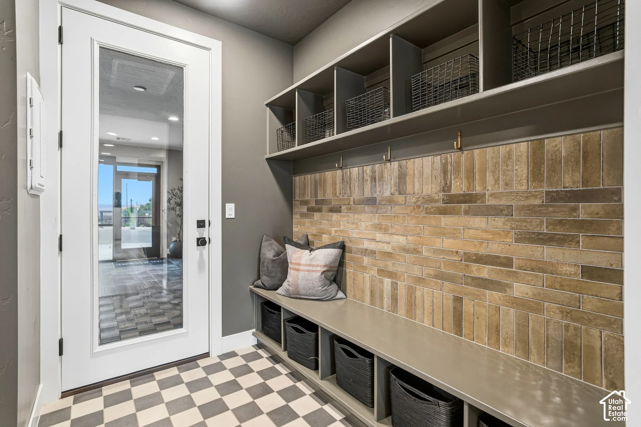 Built-in storage with a bench and shelving, complemented by a brick-patterned accent wall