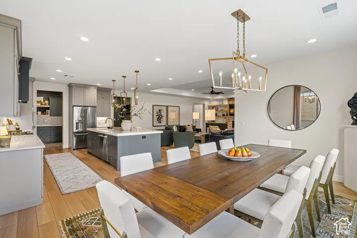 Wood-finish flooring throughout, with a dining area featuring a geometric brass chandelier and a round wall mirror