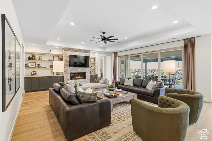 Recessed lighting, wood-finish flooring, stone fireplace, built-in shelving, and sliding glass doors