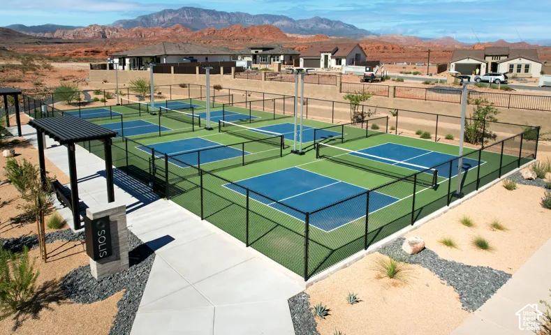 Multiple fenced pickleball courts, covered seating structure, and hardscaping with drought-tolerant plantings