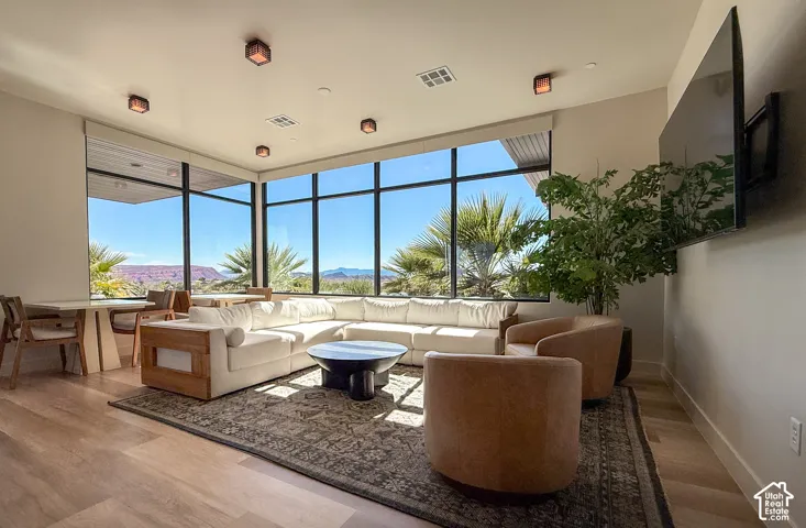 Spacious room featuring floor-to-ceiling windows, wood-finish flooring, recessed lighting, and wall-mounted light fixtures