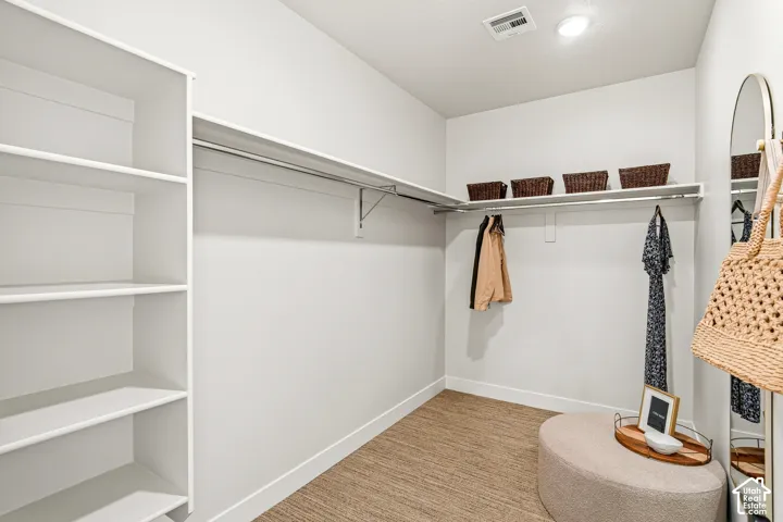 Walk-in closet featuring built-in shelving, chrome hanging rods, and recessed lighting