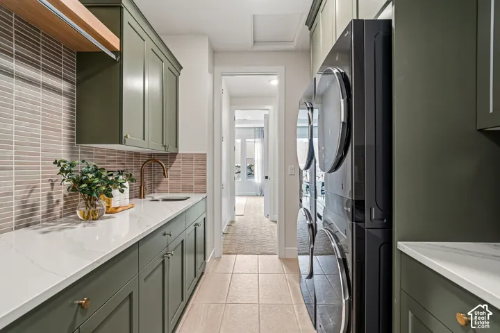 Integrated laundry area featuring olive green cabinetry, a white countertop, and a brass-finish faucet with a rectangular undermount sink