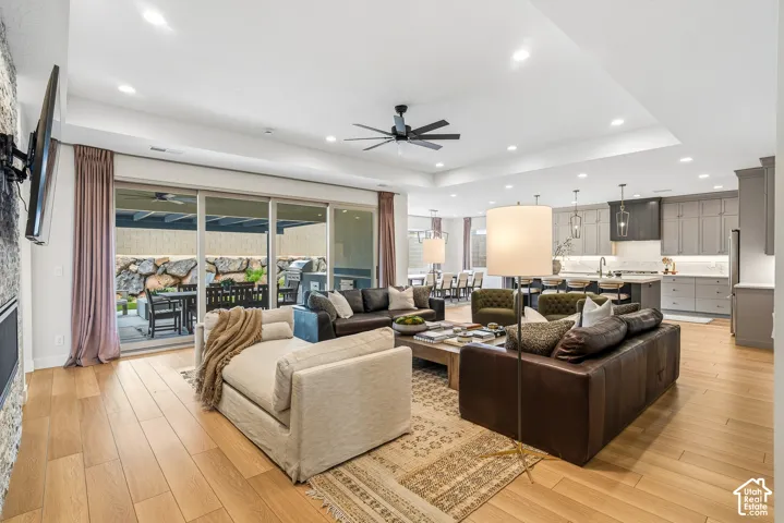 Spacious open-concept living area featuring light wood-finish flooring and a stone-clad fireplace