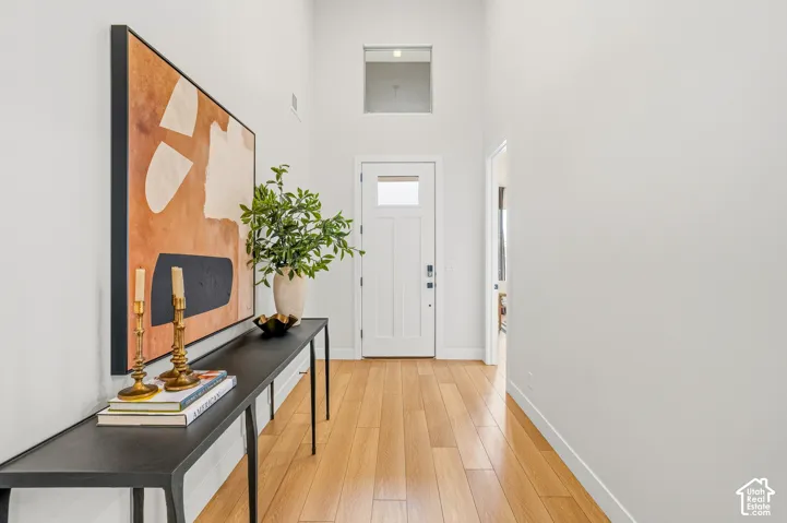 High ceilings, light wood-finish flooring, white walls, transom window, and a white paneled door