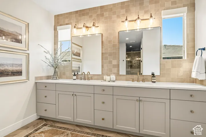 Dual vanity featuring light gray cabinetry, integrated sinks, and polished hardware