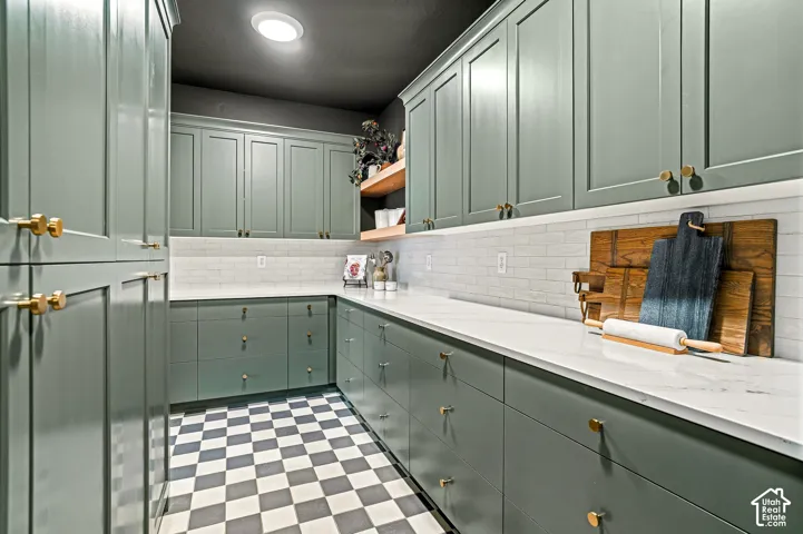 Extensive cabinetry with gold-tone hardware, white countertops, white subway tile backsplash, recessed lighting, and checkerboard floor tiling