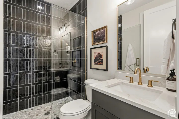 Shower with dark vertical tile, glass enclosure, and mosaic tile flooring