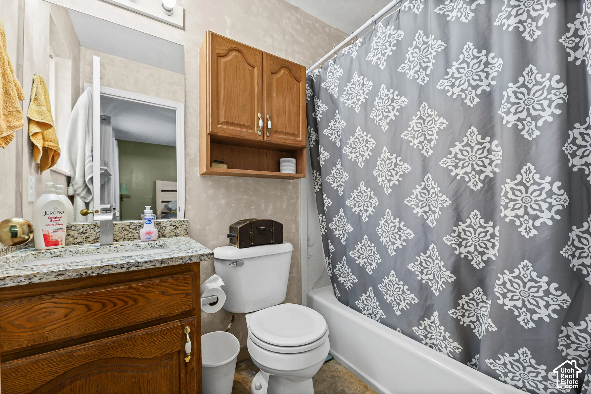 Bathroom featuring a wood-finish vanity with a speckled countertop, a built-in medicine cabinet, a full bathtub, and a toilet