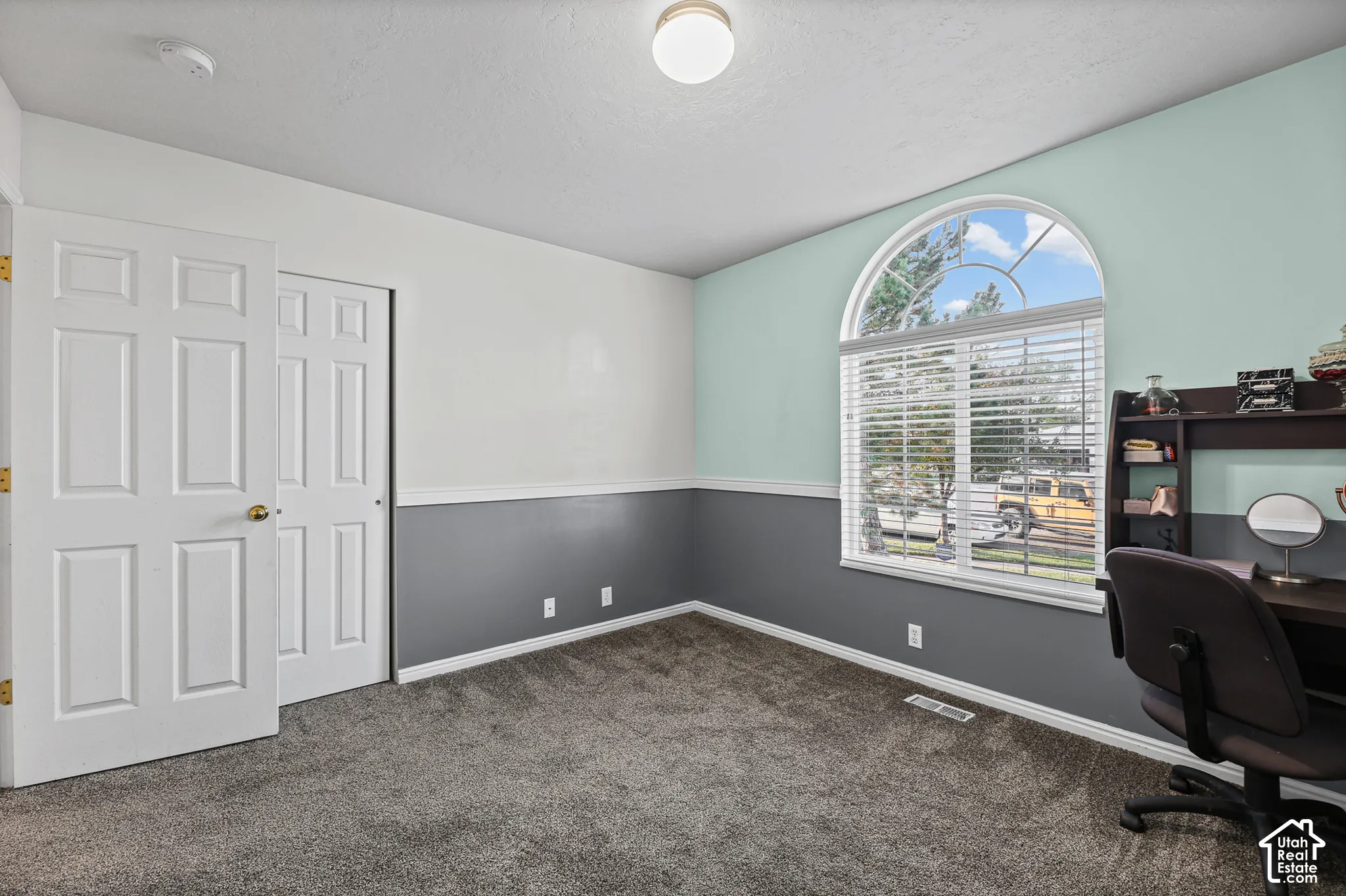 Arched window with blinds, dual-tone wall paint, wall-to-wall carpeting, and a flush mount ceiling light
