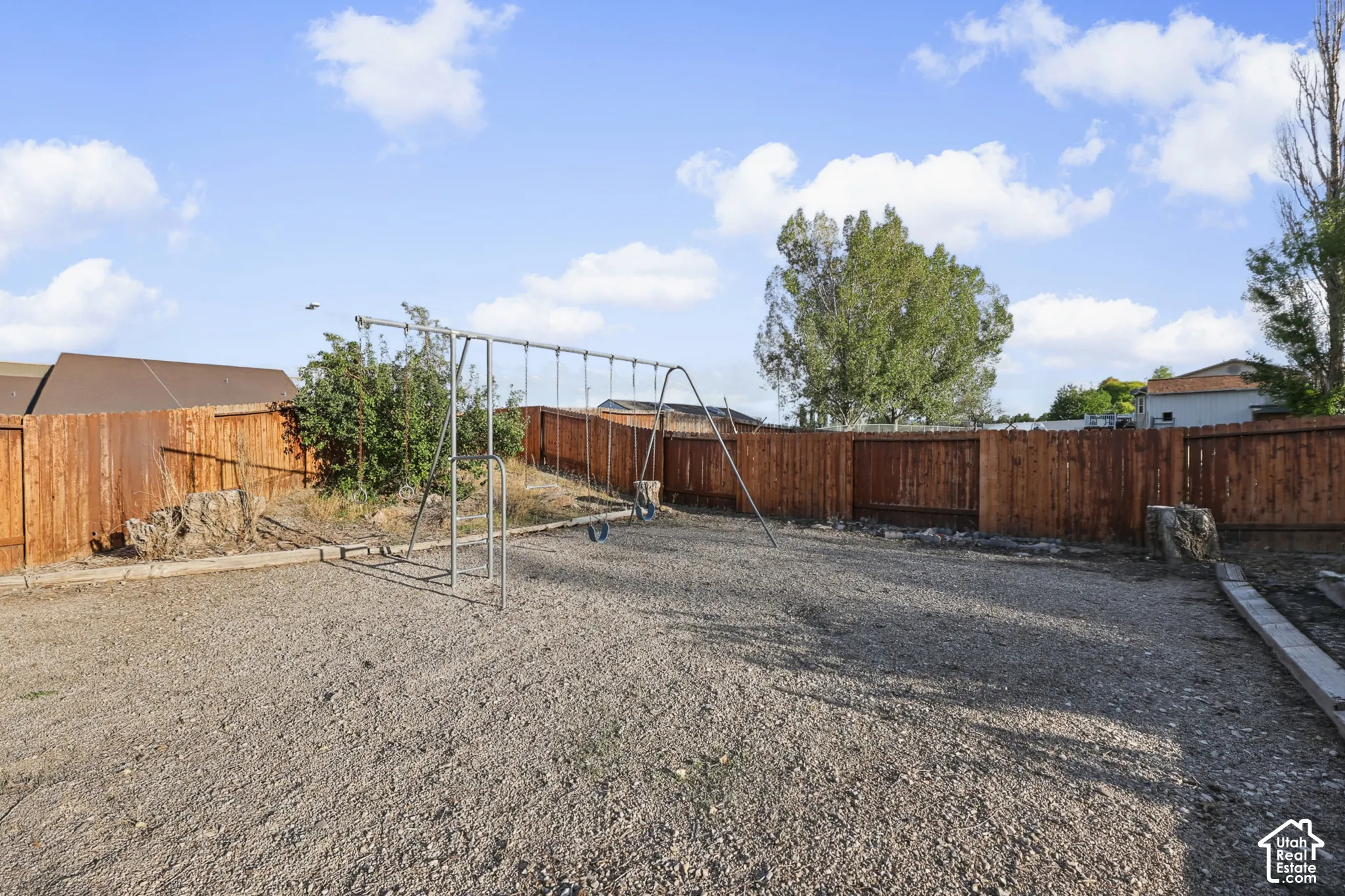 Expansive backyard with gravel surfacing, wood fencing, and mature trees