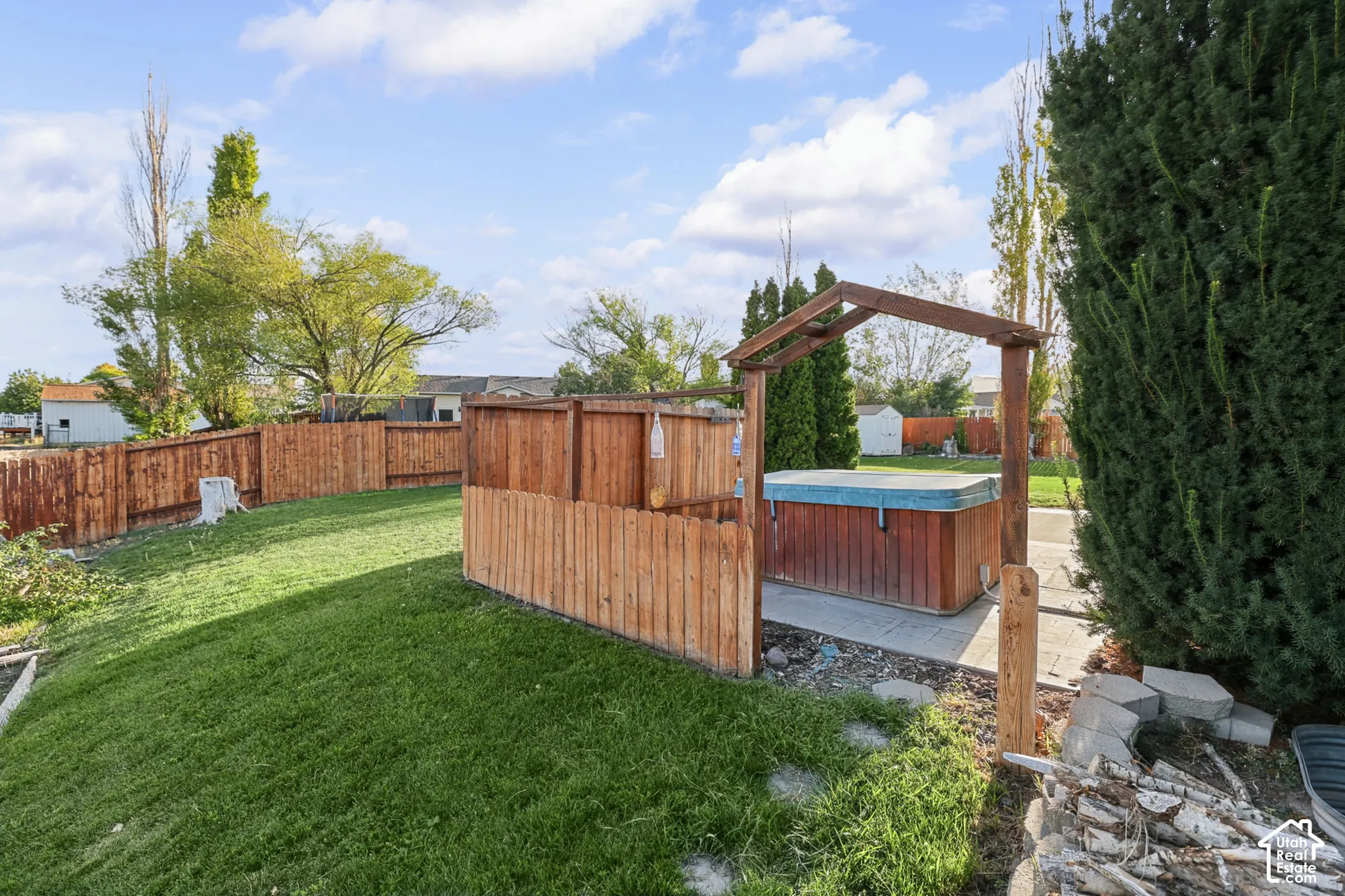 Expansive backyard featuring a hot tub with wood-finish surround, wood privacy fencing, and a manicured lawn