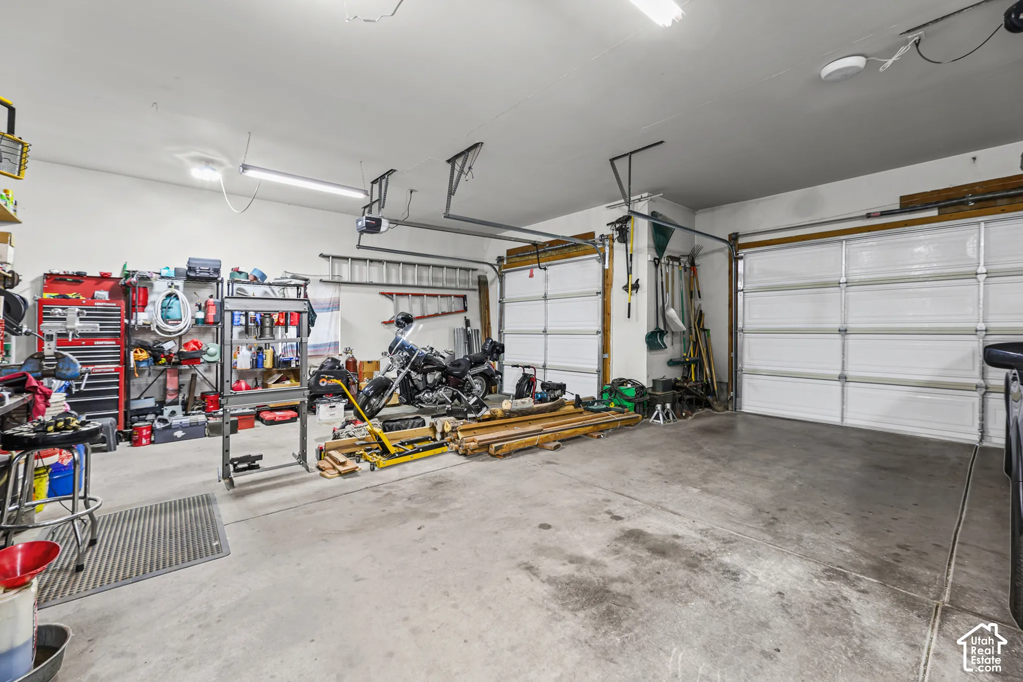 Two overhead garage doors, concrete flooring, and ceiling-mounted lighting fixtures