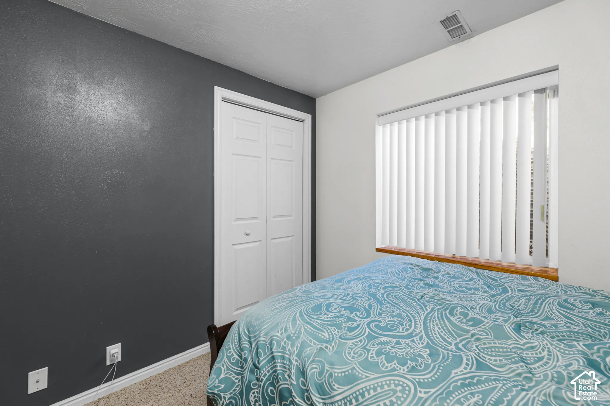 Vertical blinds on a window with a wood sill, textured accent wall, and bi-fold closet doors