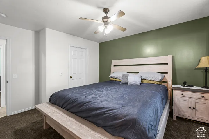 Light-toned wall paint with a contrasting accent wall, ceiling fan with integrated lighting, and carpeted flooring