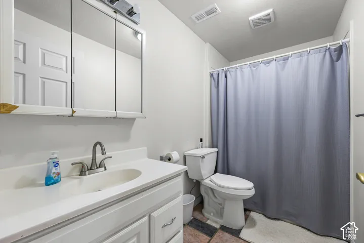 Vanity with integrated sink and chrome faucet, three-door medicine cabinet with integrated lighting, toilet, and shower area