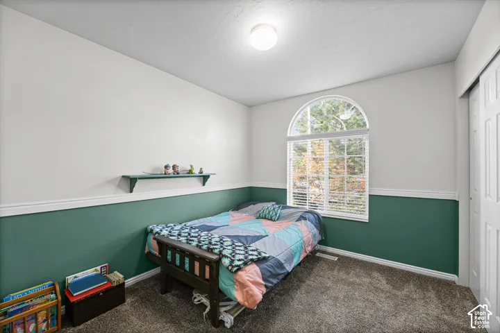 Arched window with blinds, two-tone painted walls, wall molding, built-in wall shelf, and textured carpet flooring