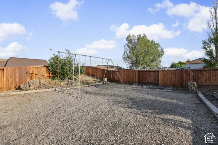 Expansive backyard with gravel surfacing, wood fencing, and mature trees