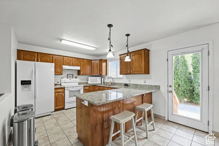 Kitchen featuring wood cabinetry, granite countertops, a central island, tile flooring, and a full-light exterior door